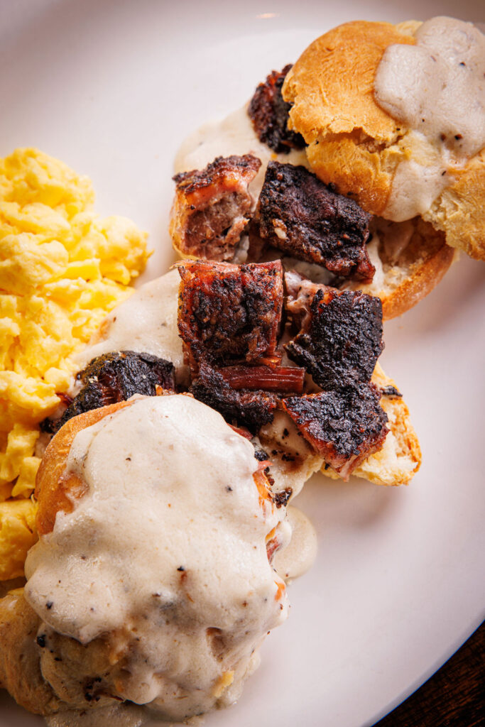 Plate of biscuits, scrambled eggs, brisket and gravy.