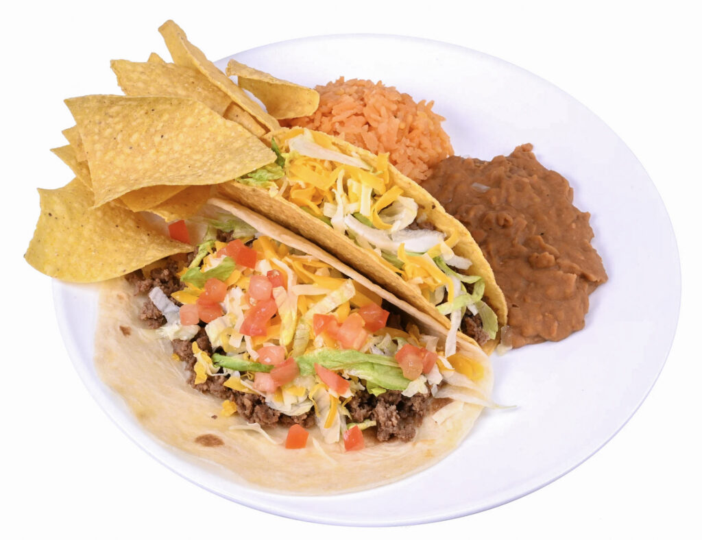 The image features a white plate filled with a delicious Mexican meal. On the plate, there are two tacos, each with a generous amount of meat and.
