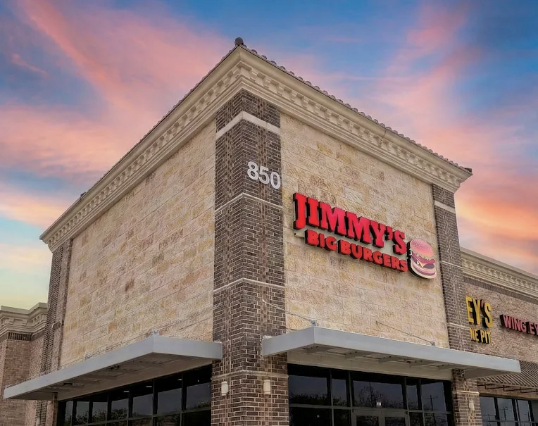 The image features a large brick building with a sign on top of it, indicating that it is a Jimmy's Big Burger restaurant.